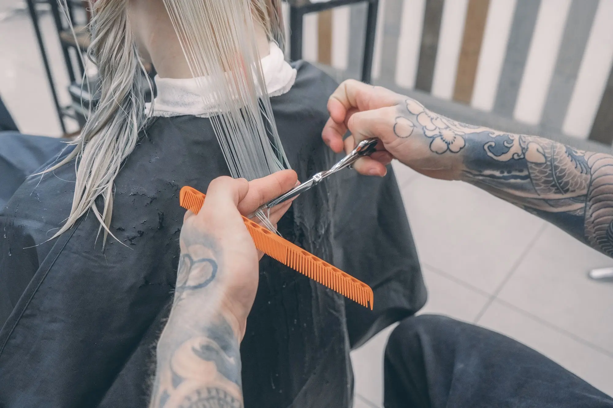 Estilista corta cabello rubio mojado con tijera y peine