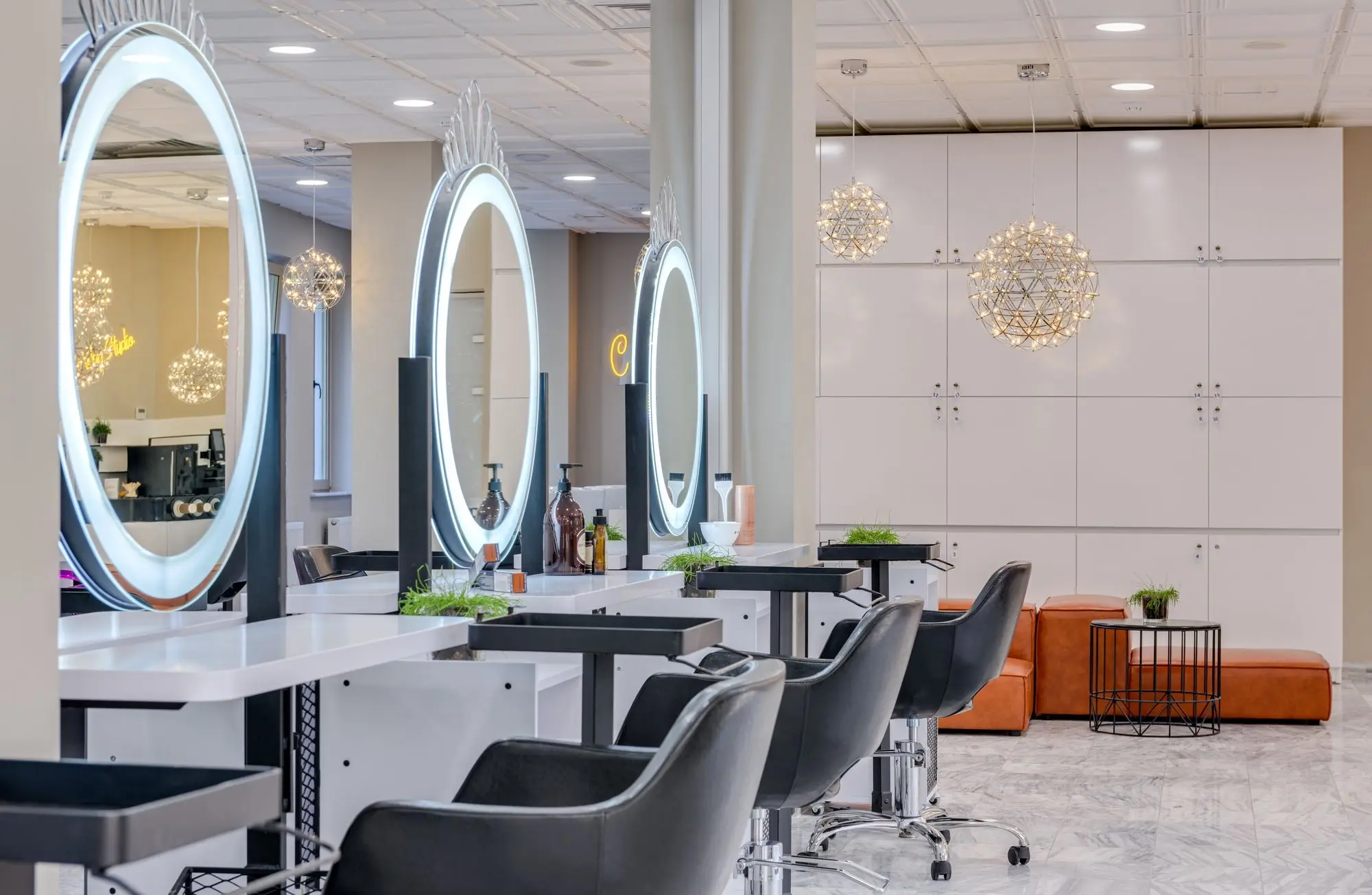 Salón luminoso con espejos redondos iluminados y sillones negros