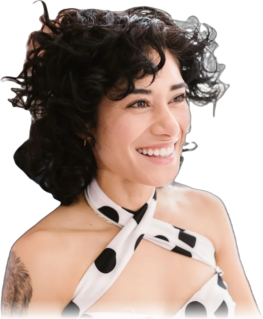 Clienta sonriente de cabello rizado mientras la estilista le acomoda el peinado