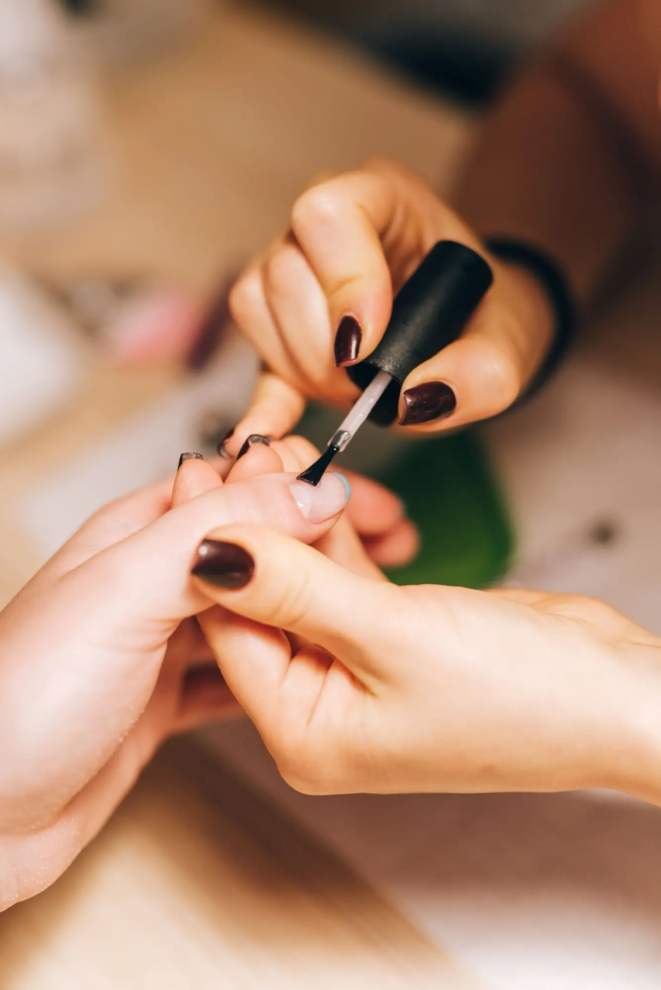 Manicurista aplica esmalte en las uñas de una clienta